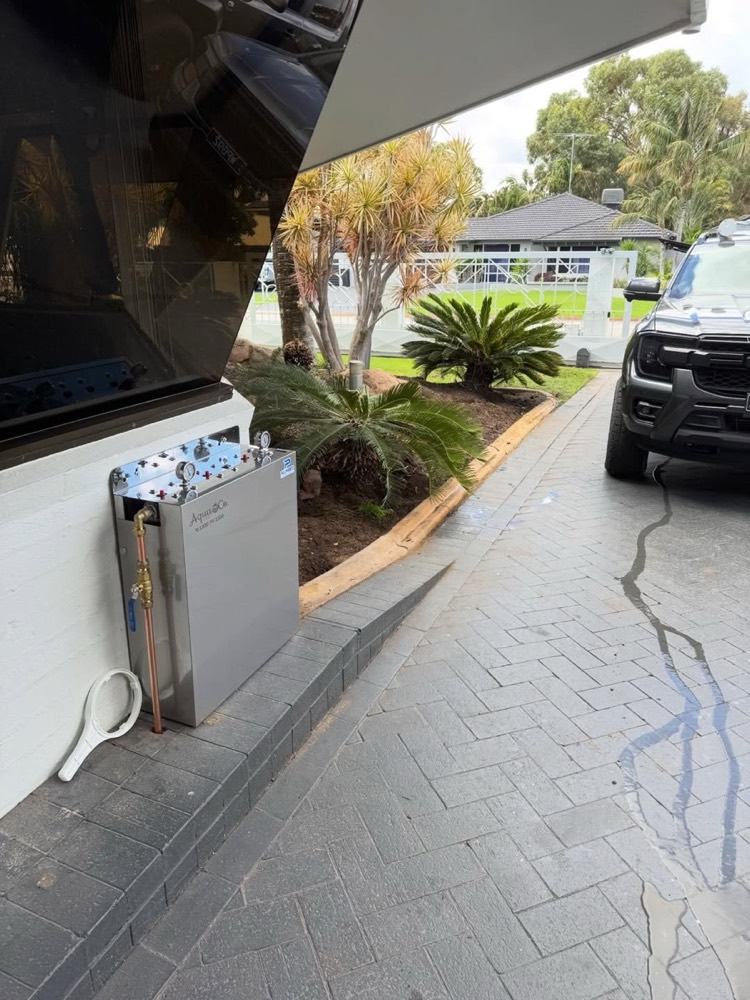 AquaCo whole-home filtration unit installed beside a driveway